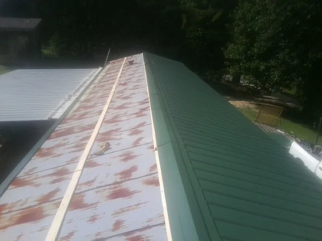 Old rusted panels beside newly installed green metal roofing — Wind Damage Roof Repair by Roofing Brothers in Beacon
