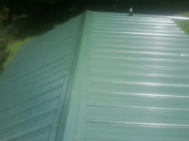 New green metal panels meeting at the ridge of a roof — Flat Roof Repair work by our crew in Beacon