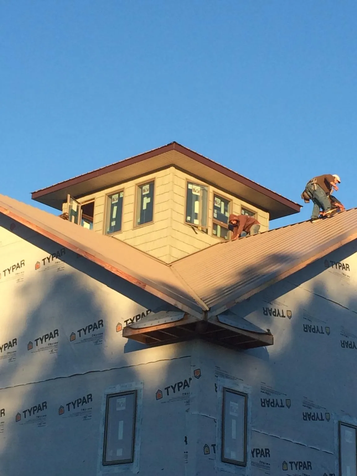 Roofers working around a rooftop cupola on a new metal roof at sunset — Roof Waterproofing in Beacon by Roofing Brothers